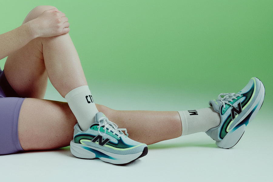 Person wearing New Balance sneakers with text 'Introducing the Ellipse' on a green background